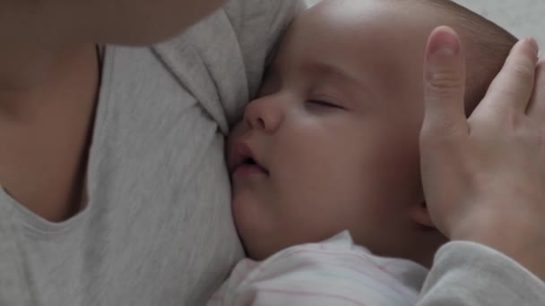 Médecine, soins de santé, famille, innocence, pédiatrie, bonheur, concepts infantiles - Gros plan Jeune mère heureuse tient dormir 7 mois fille bébé rock dans les bras et chanter berceuse assis dans la crèche sur — Video