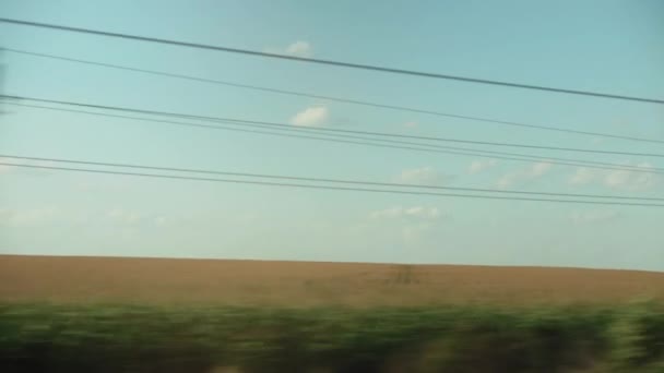 Vervoer, reizen, weg, spoorweg, landschap, comnicatie concept - uitzicht vanaf het raam van de sneltrein op het landschap van groene maïsveld elektrische palen en bos bij helder weer zomeravond — Stockvideo