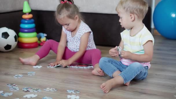 子供の頃、ゲーム、育成と開発の概念-お母さんと小さな子供の男の子の弟と女の子の妹の一般的な計画は、子供の遊び場でパズルを作ります。兄弟は隔離で家に帰るのが楽しい — ストック動画