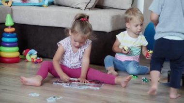 Çocukluk, oyunlar, yetiştirme ve geliştirme konsepti. Küçük çocukların genel planı. Erkek kardeş ve kız kardeş ile anne çocuk oyun odasında bulmaca çözer. Kardeşlerin karantinadaki evleri eğlencelidir.