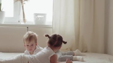 Aile, masumiyet, bebek kavramları iki gülümseyen çocuk kavga eder, oynaşırlar, yatakta dalga geçerler. Kardeşler küçük erkek ve kız kardeşler evde karantinada eğleniyor ve gülüyorlar..