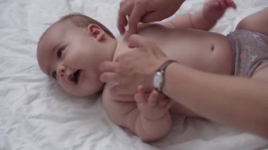 Tıp, sağlık, masumiyet, pediatri, bebek konseptleri - anne elleri yeni doğan çocuğuna bacak, ayak, parmak ve egzersiz, karın veya göğüs masajı yapar.