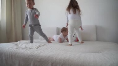 Aile, çocukluk, bebek konseptleri yeni doğmuş bebekli iki çocuk yatakta balonla atlıyor. Kardeşler küçük erkek ve kız kardeşler evde karantinada eğleniyor ve gülüyorlar.