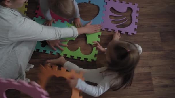 Enfance, famille, concept d'isolation - groupe deux jeunes enfants recueillent des puzzles mous fruits de grandes parties assises sur le sol. enfants Frère et sœur jouer à des jeux éducatifs pour la motricité à la maison — Video