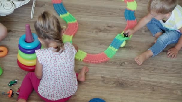 Infância, jogos, educação e conceito de desenvolvimento vista superior da mãe com bebê recém-nascido e crianças menino e menina irmã brincar com estrada mágica na sala de jogos infantil. Os irmãos se divertem em casa em quarentena — Vídeo de Stock