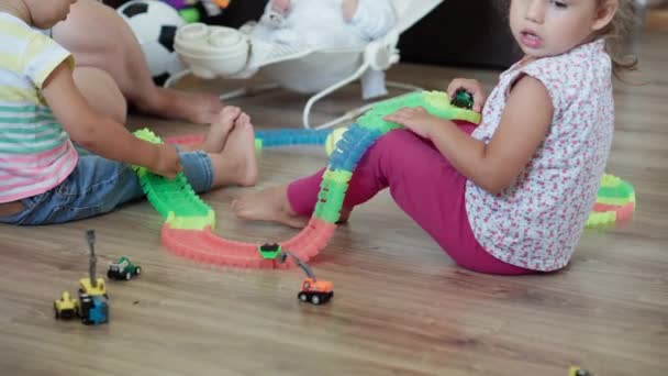 Infância, jogos, educação e conceito de desenvolvimento - plano geral da mãe com crianças menino irmão e menina irmã bebê brincar com estrada mágica na sala de jogos infantil. Os irmãos se divertem em casa em quarentena — Vídeo de Stock