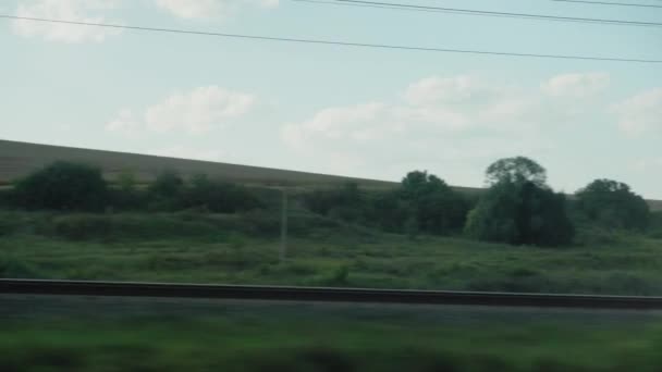 Vervoer, reizen, weg, landschap, comnicatie concept - uitzicht vanaf het raam van de sneltrein op het landschap van het natuurgebied spoorweg en oude roestige goederenwagen trein in zonnig helder weer zomeravond — Stockvideo