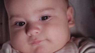 bebek, çocukluk, duygu konsepti - Kahverengi gözlü tombul bebeğin aşırı yakın plan gülen yüzü şakacı dişsiz bebek 7 aylık bebek bebek, bebek arabasında beyaz bir vücut giysisi içinde yatarken kameraya bakıyor