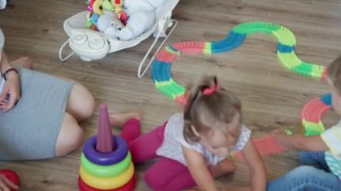 Çocukluk, oyunlar, yetiştirilme ve gelişim konsepti. Yeni doğmuş bebek ve kız kardeşle annenin çocuk oyun odasında sihirli yollarla oynaması. Kardeşler karantinada eğleniyor.