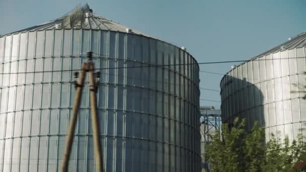 Transporte, viagens, estrada, ferrovia, paisagem, comnicação, conceito de agricultura vista da janela do trem de velocidade na paisagem do campo de natureza e silos de grãos de aço em tempo claro ensolarado noite de verão — Vídeo de Stock