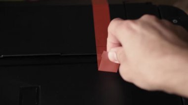 Video talimatları, teknoloji, basın, medya, ofis, kırtasiye konsepti - erkek ellerinin yeni mürekkep püskürtme yazıcıyı fırlatmaya hazırladığı yakın plan. Adım 1: turuncu ambalaj bandını ve koruyucu materyalleri kaldır