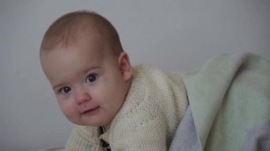Bebek, çocukluk, duygu konsepti. Kahverengi gözlü tombul bebeğin gülümseyen yüzüne yakın çekim. Sıcak süveter içinde 7 ay.