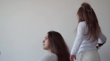 Çocukluk, annelik, kardeşlik kavramı - tasasız genç anne küçük kızının saçını tarar, oğlu ve yeni doğmuş bebeği yatakta eğlenir, neşeli aile gülüşü gıdıklanır, öpüşür, sarılır