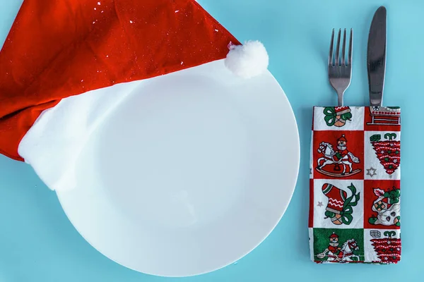 Xmas, winter, new year concept - layout white plate on which there are three Christmas trees cut from sausage cheese bread with santa hat and golden candles in form of numbers 2021 Blue background