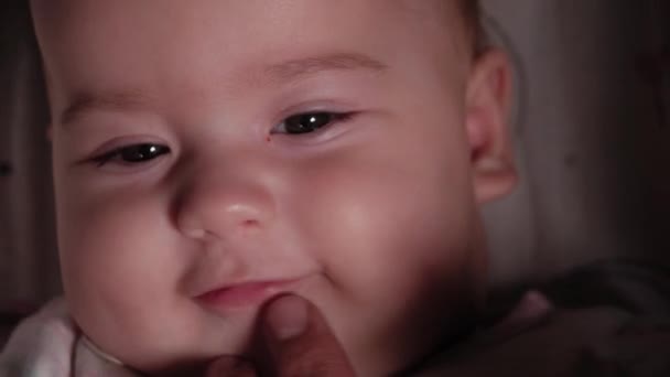 Spädbarn, barndom, känsla koncept - närbild av manliga fingret öppnar munnen leende ansikte brunögd knubbig nyfödd vaken tandlös baby 7 månader gammal i vit body suit med färgade ränder i barnvagn — Stockvideo