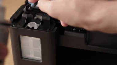 Video talimatları, teknoloji, medya, ofis, kırtasiye konsepti - erkek ellerinin yeni mürekkep püskürtme yazıcıyı fırlatmaya hazırladığı yakın plan. 10. adım: başaşağı duran iskele mürekkebine şişe hortumunu yerleştirin.