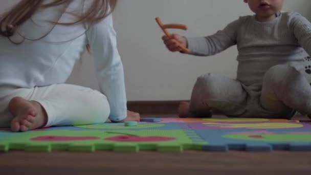 Jeugd, familie, isolatie concept - groep twee kleine kinderen verzamelen zachte puzzels fruit van grote delen zitten op de vloer. kinderen Broer en zus spelen educatieve spelletjes voor motoriek thuis — Stockvideo