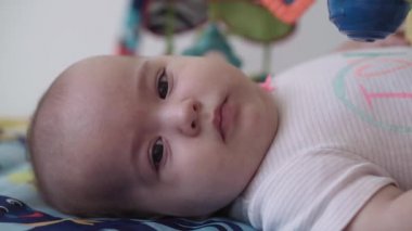 bebeklik, çocukluk, gelişim, sağlık gelişimi, yaşam tarzı konsepti - 5-8 aylık mutlu, yeni doğmuş çocuğa yaklaşın paspasın üzerinde yatarak etkinlik spor salonu bebeği içeride oyuncaklarla karnını doyuruyor