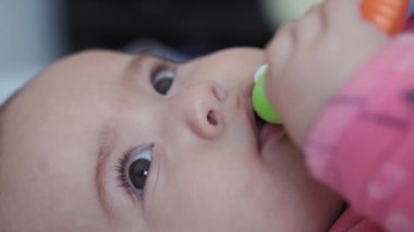 bebeklik, çocukluk, ebeveynlik, gelişim, tıp ve sağlık konsepti - ekstra yakın plan, tombul yeni doğmuş bebek, pembe vücut süitinde, çok renkli diş ekşimeleri sırtüstü uzanmış.