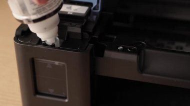 Video talimatları, teknoloji, medya, ofis, kırtasiye konsepti - erkek ellerinin yeni mürekkep püskürtme yazıcıyı fırlatmaya hazırladığı yakın plan. 10. adım: başaşağı duran iskele mürekkebine şişe hortumunu yerleştirin.