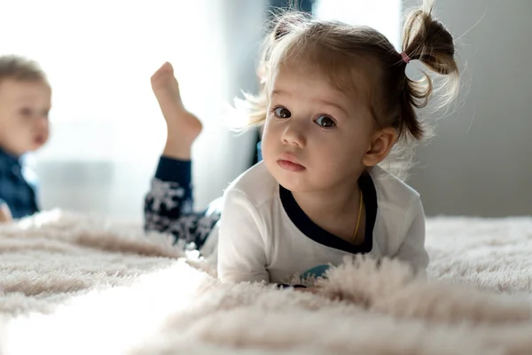 Infância, tecnologia, infantil, conceitos menores uma menina bonito bebê assistir desenhos animados no telefone, smartphone na cama branca macia no quarto ensolarado. criança em pijama falar por videoconferência em gadget dentro de casa — Fotografia de Stock