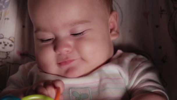 Baby, jeugd, emotie concept - close-up van schattige glimlach gezicht van bruin-eyed mollig pasgeboren wakker tandeloze baby 7 maanden oud kijken naar camera liggend in wit lichaam pak met grote bijtring in kinderwagen — Stockvideo