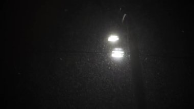Hava tahmini, anormallik, acil durum, element, kış konsepti. Kar yağışının sabit olmayan el kamerasıyla çekilmesi. Gece parkındaki sokak lambalarının sarı ışığında düşen kar taneleri. Kiev 'deki ilk kar
