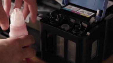 Video talimatları, teknoloji, medya, ofis, kırtasiye konsepti - erkek ellerinin yeni mürekkep püskürtme yazıcıyı fırlatmaya hazırladığı yakın plan. 10. adım: başaşağı duran iskele mürekkebine şişe hortumunu yerleştirin.
