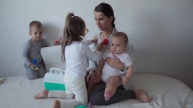 Tıp, aile, oyun konseptleri konsantre, oyuncu aile çocukları tıbbi gözlük takıyor. Doktor gibi davran hemşire, dinle anne yeni doğmuş bebek kız kardeşin derin derin nefes al, yatağa otur..