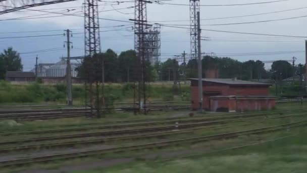 Vervoer, reizen, weg, landschap, comnicatie concept - uitzicht vanaf het raam van de sneltrein op het landschap van het natuurgebied spoorweg en oude roestige goederenwagen trein in saai bewolkt weer zomeravond — Stockvideo