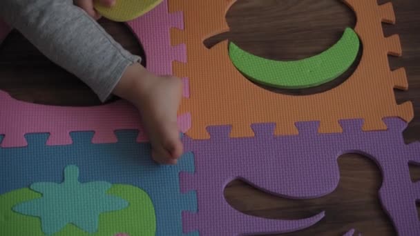 어린 시절, 가족, 절연 개념 - 두 명의 어린 자녀가 바닥에 앉아 있는 커다란 부분의 부드러운 퍼즐 열매를 모은다. 어린이와 자매가 집에서 운동 기술을 배우기 위해 교육용 게임을 하는 모습 — 비디오
