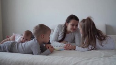 Çocukluk, annelik, kardeşlik kavramı, tasasız genç anne, küçük çocuklar için kitap perisi kuyrukları, yeni doğan bebek, yatakta iyi eğlenceler, neşeli aile gülüşleri, gıdıklanmalar, öpücükler, kucaklaşmalar.