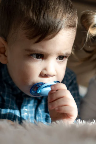 Enfance, famille, solitude concepts - Petit garçon noir d'âge préscolaire en vêtements bleus Perse apparence arabe de deux ans de nationalité mixte assis sur un lit léger doux avec sucette dans la bouche à la maison — Photo