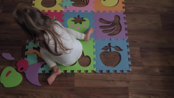 Infância, família, conceito de isolamento - grupo duas crianças pequenas coletam quebra-cabeças suaves frutos de grandes partes sentadas no chão. crianças Irmão e irmã jogando jogos educativos para habilidades motoras em casa — Vídeo de Stock