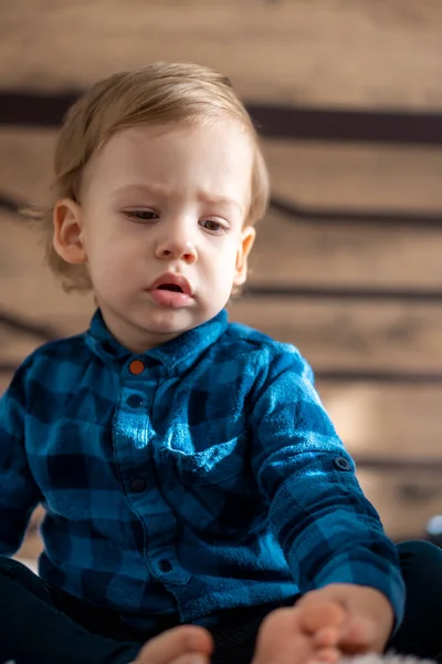 Enfance, bébé, concepts mineurs - fermer une blonde aux yeux noirs triste, offensé bébé garçon sur lit poudré doux dans la chambre ensoleillée. portrait embarrassé préscolaire slave enfant en chemise à la maison à l'intérieur — Photo