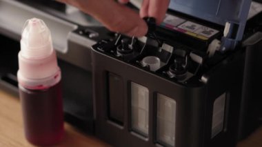 Video talimatları, teknoloji, medya, ofis, kırtasiye konsepti - erkek ellerinin yeni mürekkep püskürtme yazıcıyı fırlatmaya hazırladığı yakın plan. 10. adım: başaşağı duran iskele mürekkebine şişe hortumunu yerleştirin.