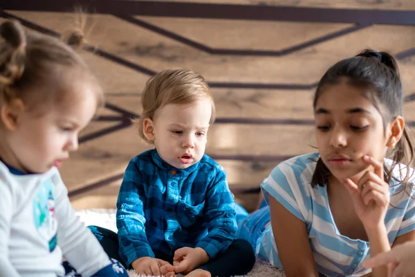 Φιλία, την παιδική ηλικία, την τεχνολογία έννοιες - 3 μικρά παιδιά μωρό διαφορετικών εθνικοτήτων Περσική και Σλαβική εμφάνιση παρακολουθήσουν κινούμενα σχέδια στο smartphone στο κρεβάτι. παιδιά προσχολικής ομιλίας από το βίντεο συνέδριο — Φωτογραφία Αρχείου