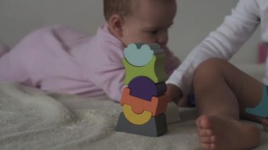 Çocukluk, aile, izolasyon, inşaat konsepti - 2 küçük mutlu çocuk yatağa oturmuş ahşap piramit inşa ediyor. 6-9 aylık yeni doğmuş kız çocuğu ve 2-3 yaşındaki oğlan evde motor becerileri için oyun oynuyorlar..