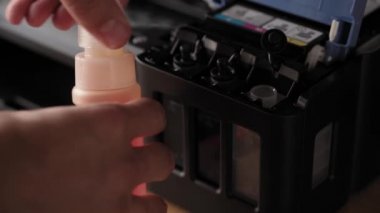 Video talimatları, teknoloji, medya, ofis, kırtasiye konsepti - erkek ellerinin yeni mürekkep püskürtme yazıcıyı fırlatmaya hazırladığı yakın plan. 10. adım: başaşağı duran iskele mürekkebine şişe hortumunu yerleştirin.