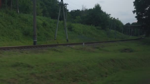 Transport, voyage, route, paysage, concept de communication - vue depuis la fenêtre du train de vitesse sur le paysage de la nature champ ferroviaire et vieux train rouillé de wagons de marchandises par temps nuageux soirée d'été — Video