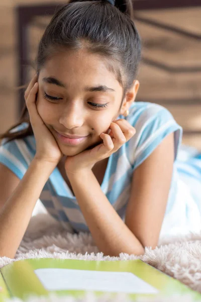 Infancia, emociones, soledad, concepto de belleza - retrato de feliz joven menor alegre alegre niña de piel oscura de aspecto persa de Oriente Medio 6-9 años sonriendo cutely tumbado en la cama en el interior. — Foto de Stock