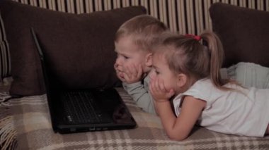 Aile, oyun, karantina, çocukluk kavramları iki mutlu çocuk karantina sırasında evdeki kahverengi kanepede dizüstü bilgisayar izleyip çizgi film izliyor. Çocuklar erkek kardeşler, kız kardeşler birlikte eğlenin.