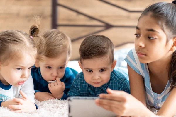 Arkadaşlık, çocukluk, teknoloji kavramları. Farklı milletlerden 4 çocuk. Farsça ve Slav görünümlü bebekler. Çocuklar anaokulunda video konferansına göre konuşuyor