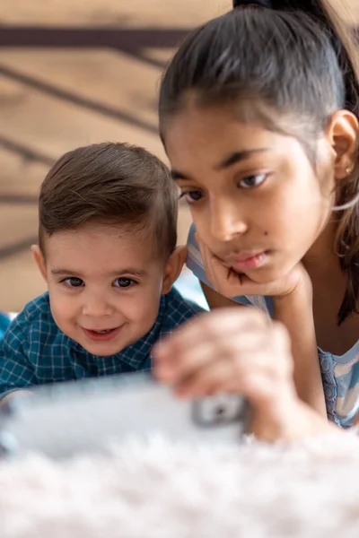 Amistad, infancia, conceptos tecnológicos - 2 niños pequeños bebé de diferentes nacionalidades persa y eslava apariencia ver dibujos animados en el teléfono inteligente en la cama. niños preescolares hablan por videoconferencia — Foto de Stock