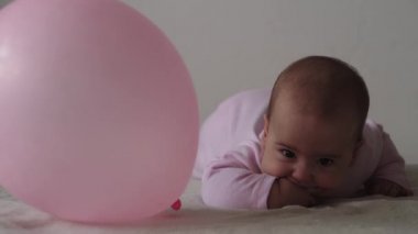 Bebek, çocukluk konsepti, gülümseyen mutlu tombul, kahverengi gözlü, yeni doğmuş çocuğun tombul yüzünün yakın çekimi. Dişsiz 7 ay bebek buruşuklukları, gözlerini kapatır yumuşak yatağa uzanır pembe kemiren parmaklar yatakta