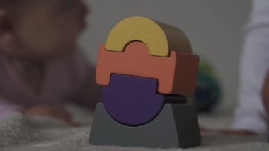 Çocukluk, aile, izolasyon, inşaat konsepti - 2 küçük mutlu çocuk yatağa oturmuş ahşap piramit inşa ediyor. 6-9 aylık yeni doğmuş kız çocuğu ve 2-3 yaşındaki oğlan evde motor becerileri için oyun oynuyorlar..