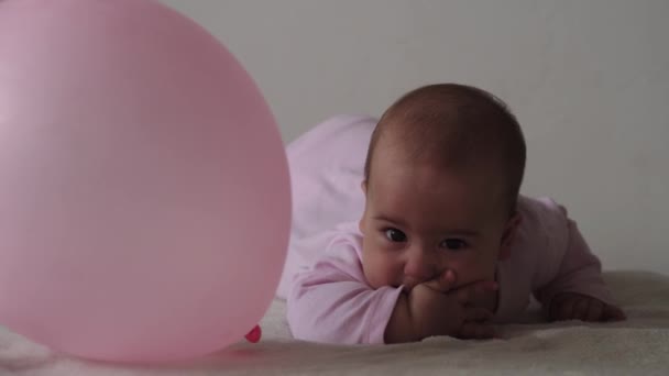 Немовля, концепція дитинства крупним планом усміхнене щасливе пухке смішне пухке обличчя новонародженої дитини прокинулося. беззубий 7-місячний дитячий похмілля, закриває очі лежать на м'якому ліжку в рожевих гвоздиках пальцями на ліжку — стокове відео