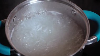 Yemek pişirme, restoran, mutfak, yemek pişirme, ev hanımı kavramları - beyaz makarna çekirdeklerini yakından görmek elektrikli indüksiyon tabağında kaynatılır. Kadın tuzlama yemeği. Mutfakta akşam yemeği ve esrar.