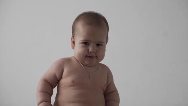 Bébé, concept d'enfance - enfant tout-petit amusant et heureux 8 mois bébé nake apprendre à s'asseoir seul jouer sur un lit blanc. joie souriante potelée actif éveillé applaudissements mains à l'intérieur à la maison sur fond blanc — Video