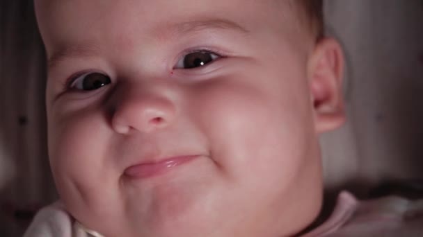 Neonato, infanzia, concetto di emozione primo piano di carino viso sorridente di paffuto occhi marroni neonato sveglio bambino sdentato 7 mesi guardando la fotocamera sdraiato in body bianco con grande dentifricio nel passeggino — Video Stock